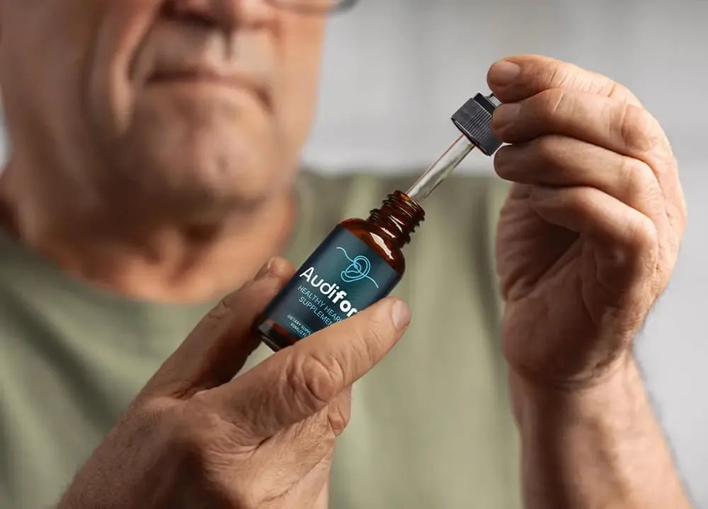 Person holding Audifort hearing support supplement bottle
