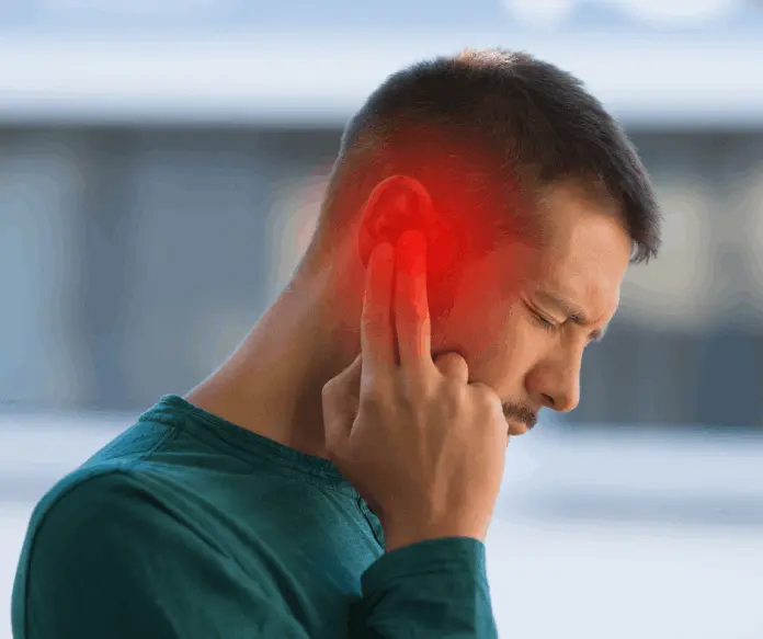 Man experiencing tinnitus holding his ear in discomfort